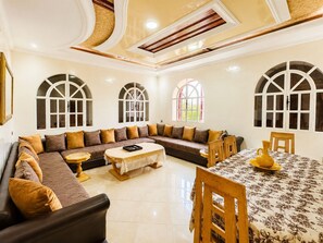 A spacious living area with a large sectional sofa, a coffee table, and a dining table with chairs.