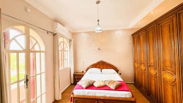 A bedroom with a large bed, a wardrobe, and a chandelier.