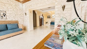 A hotel lobby with a wooden reception desk, a blue sofa, and a stone wall.