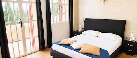A bedroom with a bed, a nightstand, a lamp, and a window with curtains.