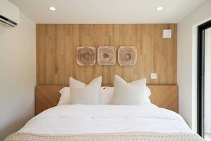 A bedroom with a wooden headboard, a bed with white bedding, and three circular wall decorations. - Private, modern house with fireplace & hot tub (Harbor Springs)