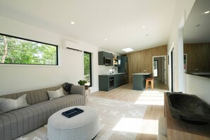 A modern interior with a sofa, ottoman, kitchen, and dining area. - Private, modern house with fireplace & hot tub (Harbor Springs)