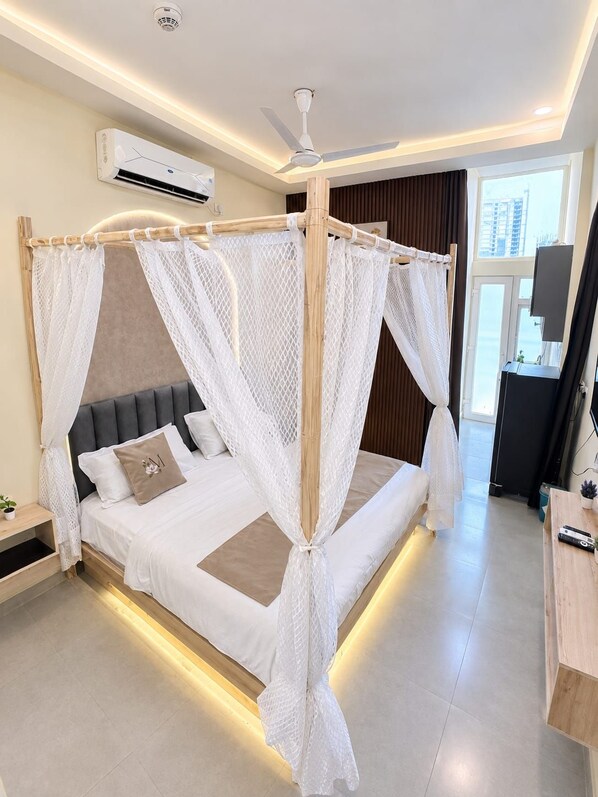 A modern bedroom with a canopy bed, a ceiling fan, and an air conditioning unit.