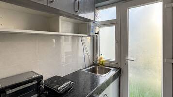 Une cuisine moderne dotée d’un four encastré, d’un évier et d’une fenêtre offrant une vue sur le ciel.