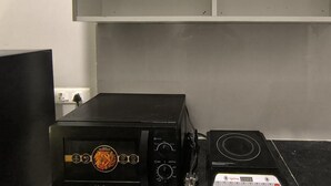Una cocina con armarios blancos, un microondas negro y una estufa.