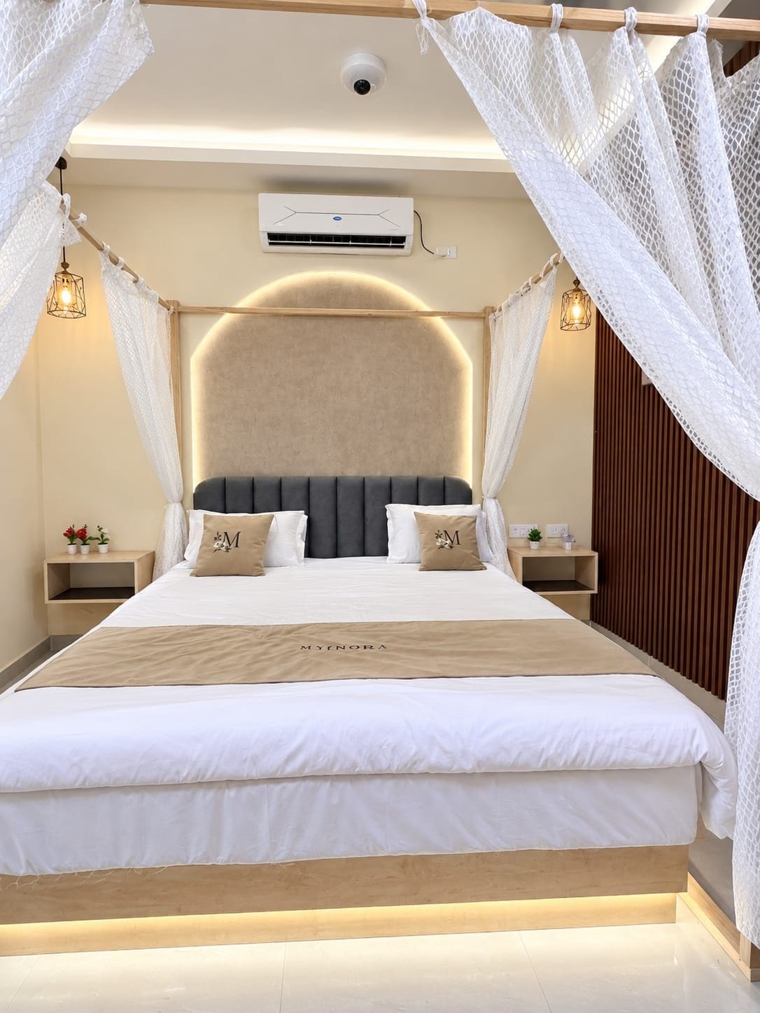 Un dormitorio moderno con una cama grande, cabecera, mesitas de noche y dosel.