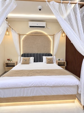 A modern bedroom with a large bed, a headboard, bedside tables, and a canopy.
