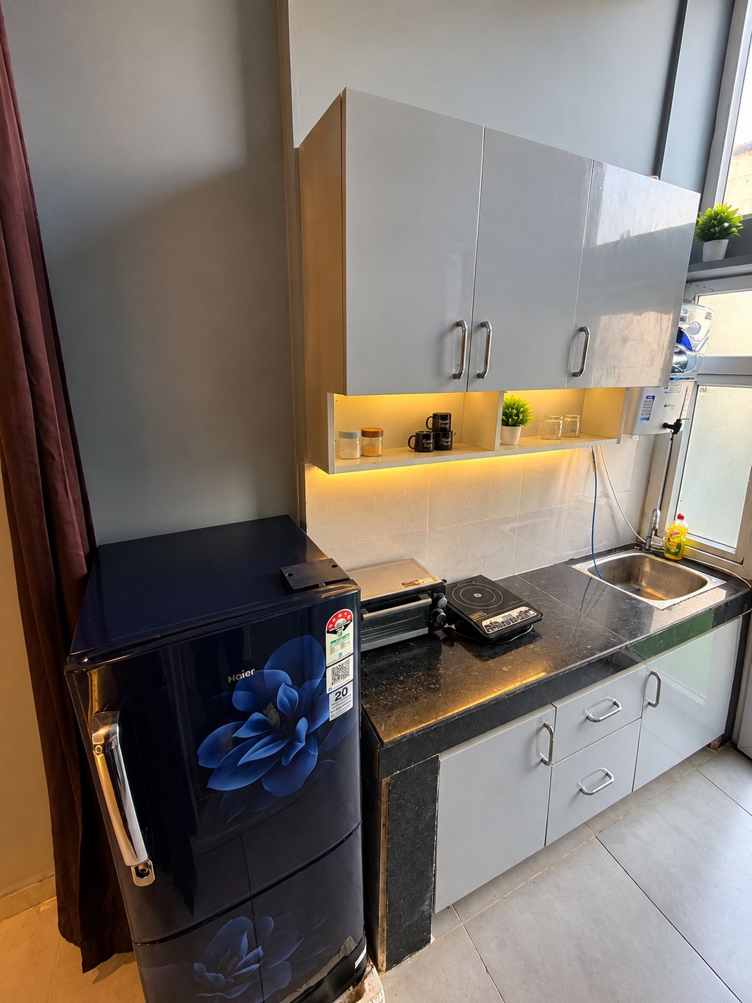 Una cocina pequeña equipada con refrigerador, cafetera y lavabo.