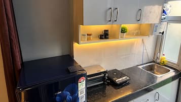 Una cocina pequeña equipada con refrigerador, cafetera y lavabo.