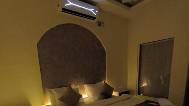 Una habitación de hotel moderna con una cama grande, cabecera y mesita de noche.