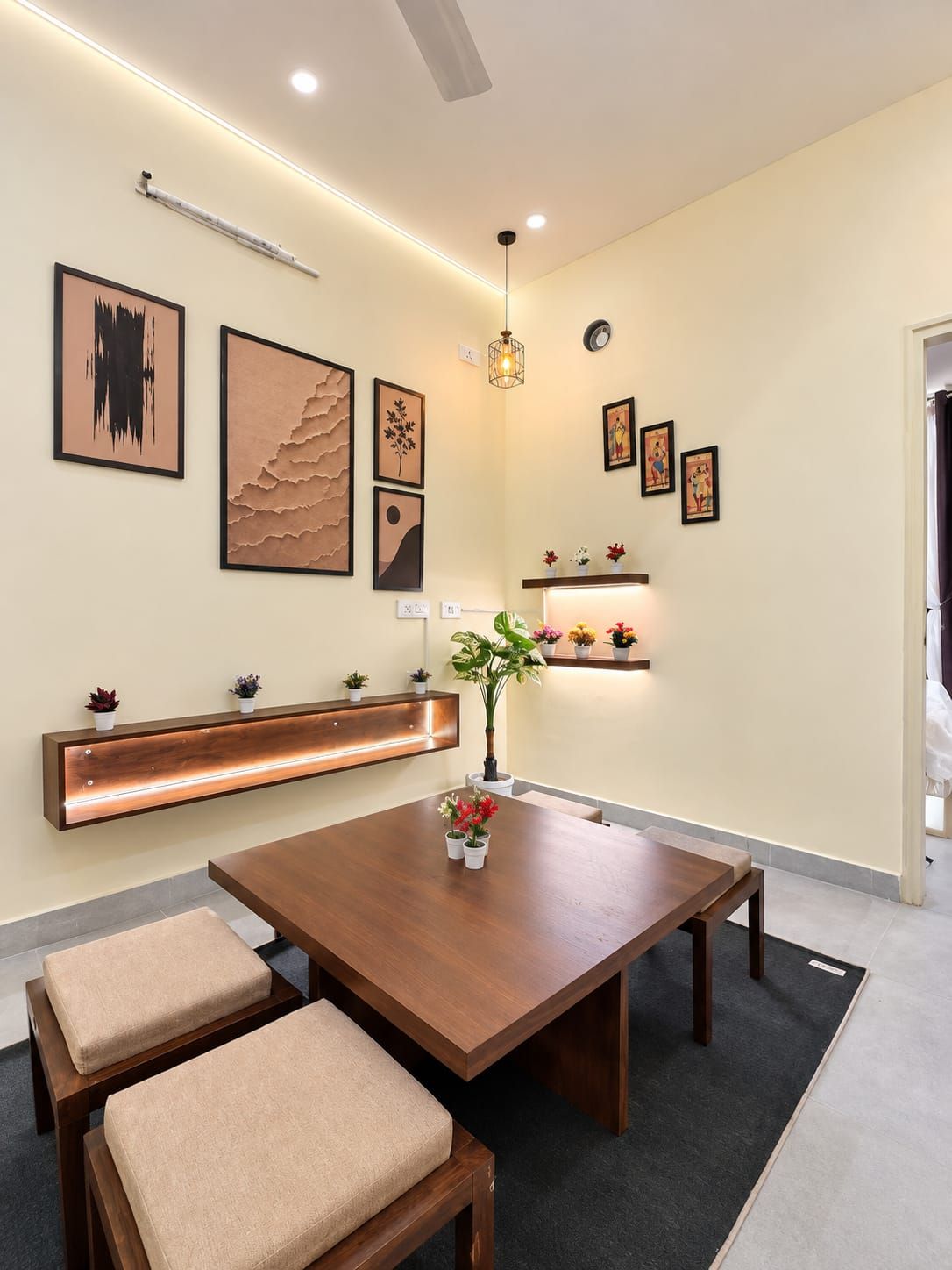 A modern dining area with a wooden table, cushioned benches, and a variety of wall-mounted art pieces.