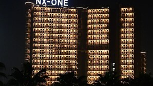 Un edificio de hotel de varios pisos con un llamativo letrero 'NX-ONE' en la parte superior.