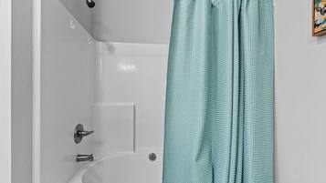 Ein Badezimmer mit einer Badewanne, einer Duschvorhang und einem Wasserhahn.