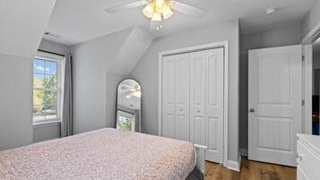 A bedroom with a bed, a ceiling fan, a wardrobe, and a mirror.