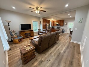 A spacious living room with a large leather sofa, wooden coffee table, and a television. - Walk to Boat Ramp Lake Keowee w/ Parking + Firepit (Seneca)