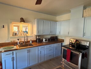 A kitchen with light blue cabinets, a stainless steel oven, and a wooden countertop. - Wonderful 2-bedroom farmhouse in Salida.  Located @  Historic Hutchinson Ranch (Salida)
