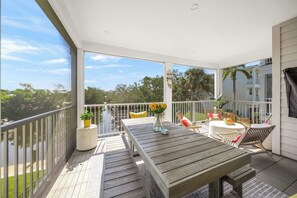 Eine Holzterrasse mit Tisch und Stühlen, die auf ein Wohngebiet mit Bäumen und bewölktem Himmel blickt.
