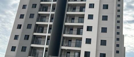 Un immeuble de grande hauteur doté de nombreux balcons et d’un élément vertical central.