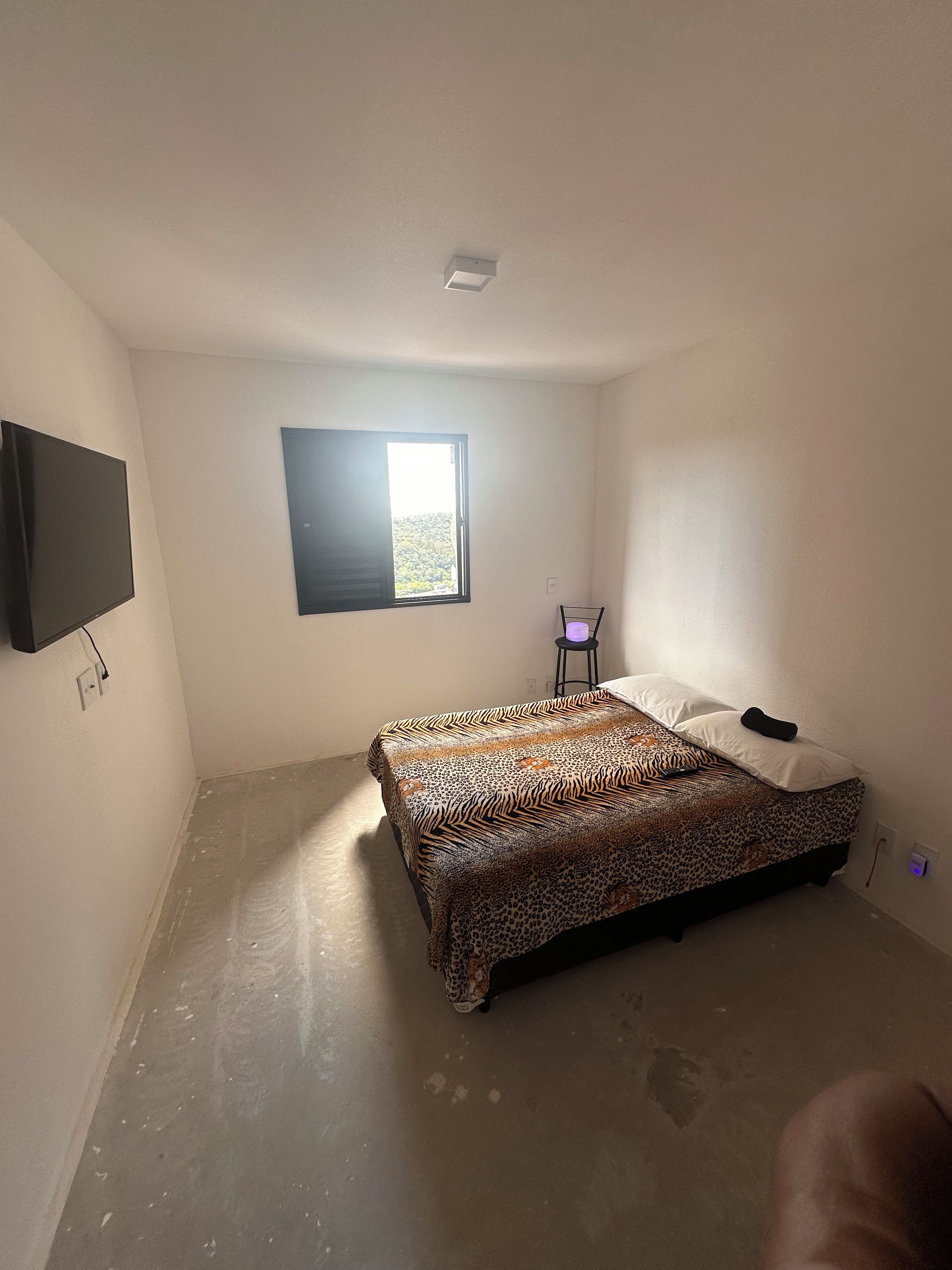 Una camera da letto con un letto, una televisione, una finestra e una sedia.