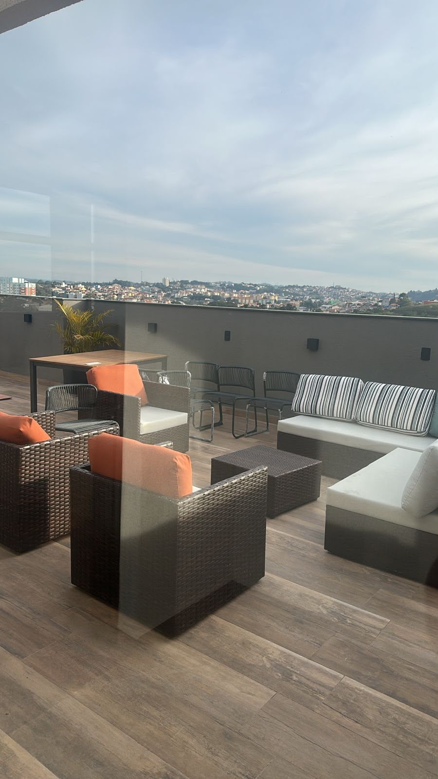 Una terrazza sul tetto con mobili in vimini, un divano e vista sulla città.