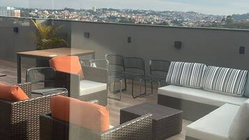 Una terrazza sul tetto con mobili in vimini, un divano e vista sulla città.