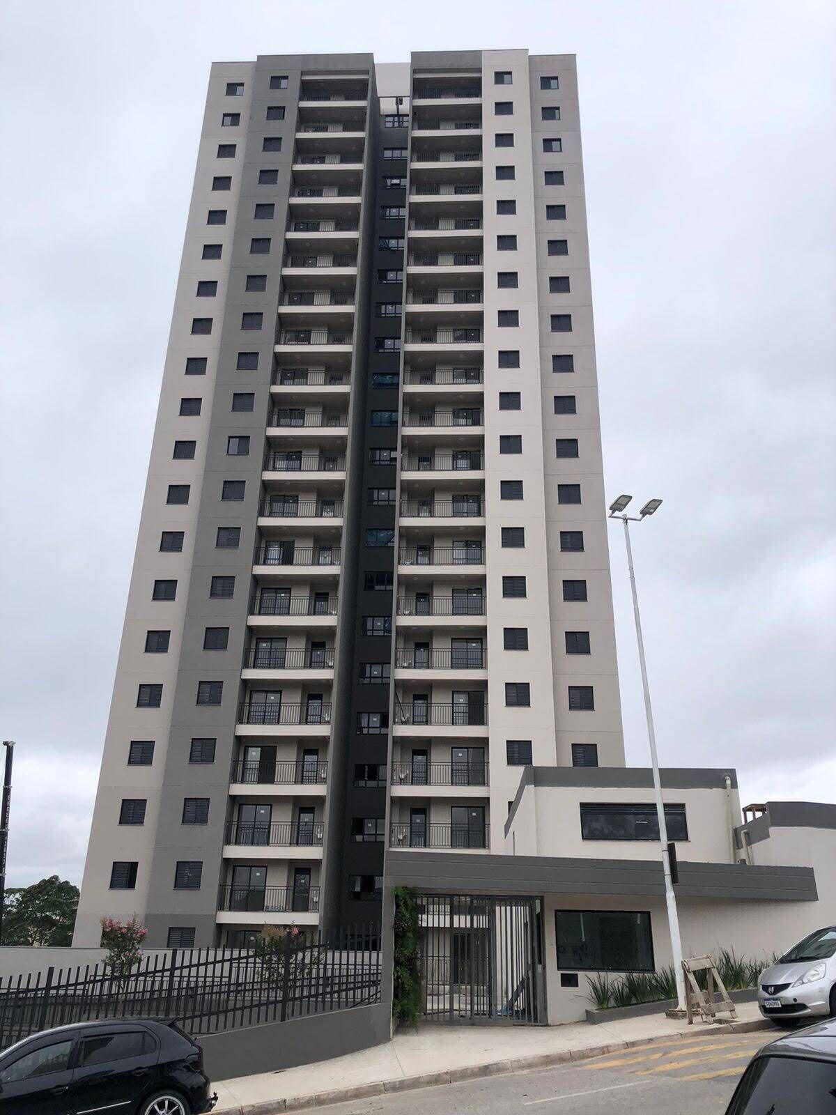 Un immeuble résidentiel de grande hauteur doté de nombreux balcons, d’une entrée sécurisée et d’un lampadaire.