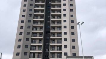 Un immeuble résidentiel de grande hauteur doté de nombreux balcons, d’une entrée sécurisée et d’un lampadaire.
