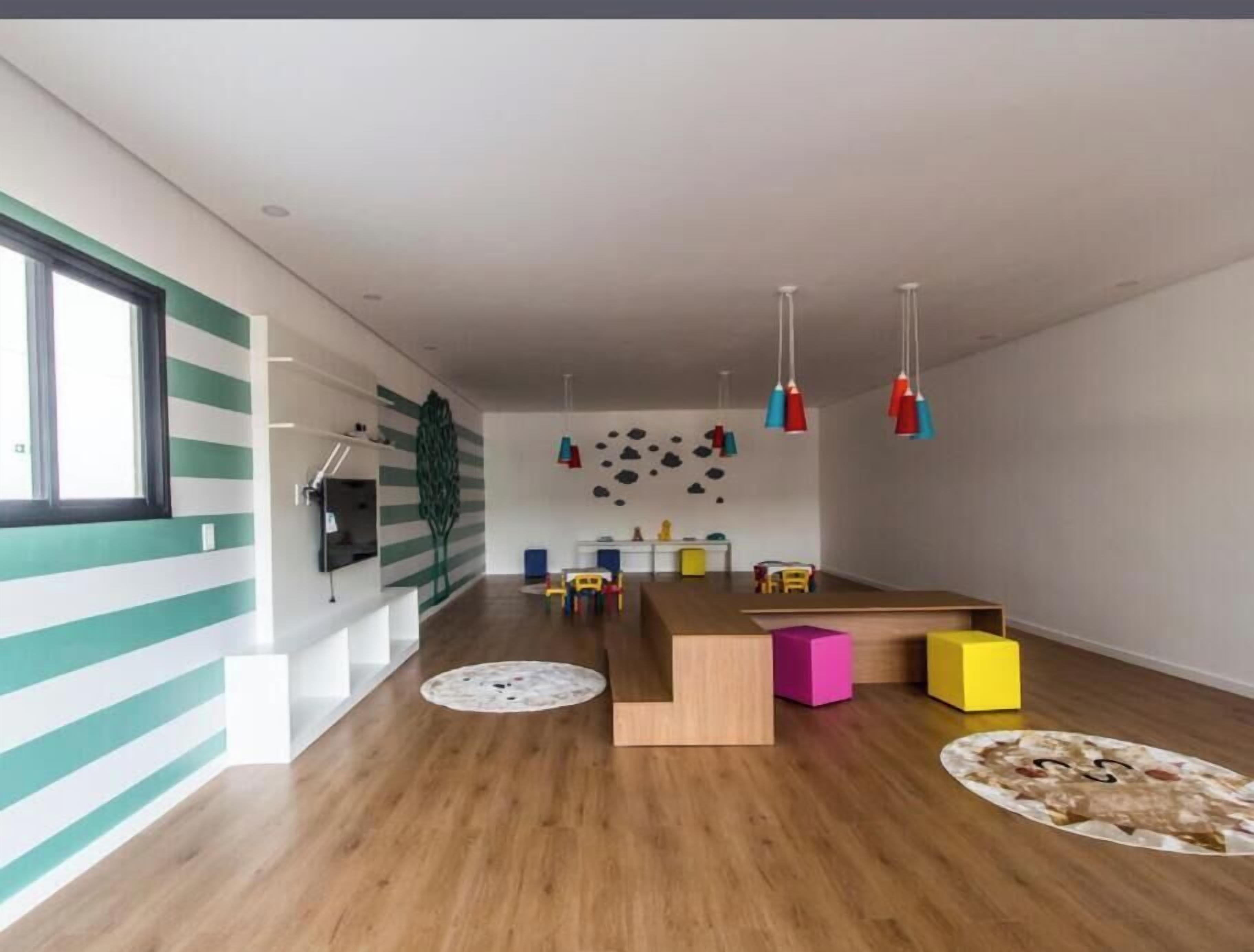 Un intérieur moderne avec un plancher en bois, une table centrale en bois, des blocs de couleurs vives et des luminaires suspendus.