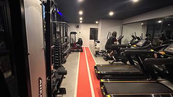 A gym with treadmills, weight machines, and a red running track.