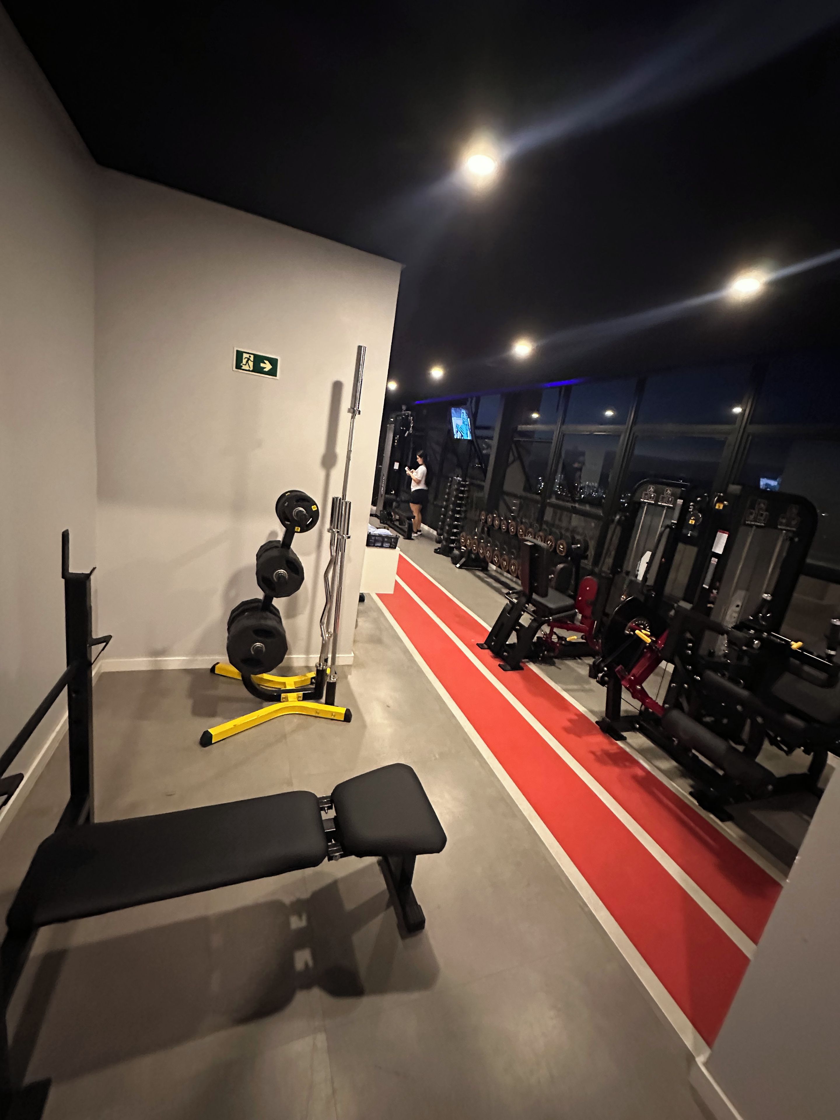 A gym with a bench, weight racks, and exercise machines.