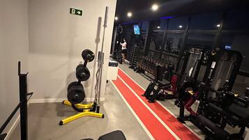 A gym with a bench, weight racks, and exercise machines.