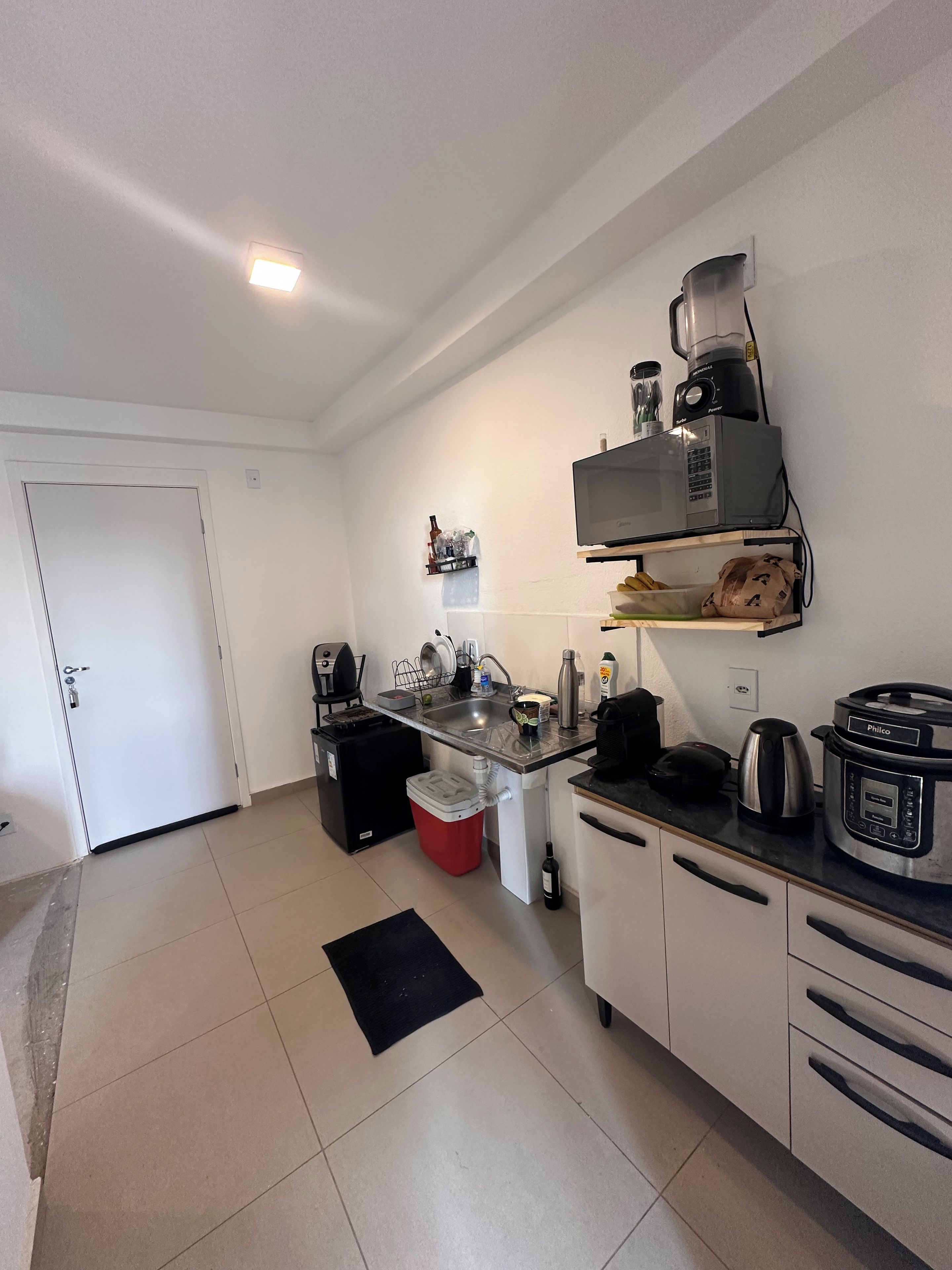 A compact kitchen with a sink, a coffee maker, a blender, and a rice cooker.