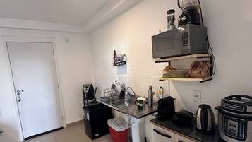 A compact kitchen with a sink, a coffee maker, a blender, and a rice cooker.