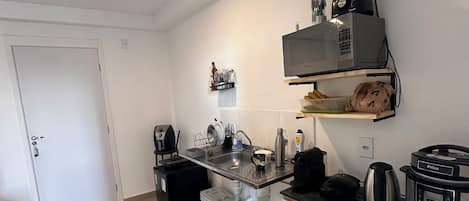 A compact kitchen with a sink, a coffee maker, a blender, and a rice cooker.