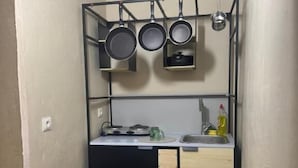 A compact kitchen with a black countertop, a sink, and a pot rack above. - Katmani Hotel (ARTUKLU)