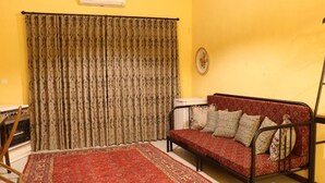 Una habitación con sofá, alfombra estampada y cortina.