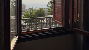Una habitación con un ventanal, vistas de la ciudad y un balcón con barandilla de metal.