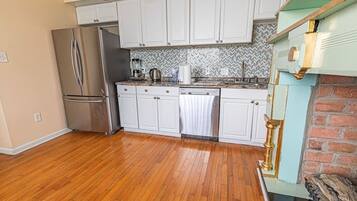 A kitchen with white cabinets, a stainless steel refrigerator, a dishwasher, and a herringbone-patterned backsplash.