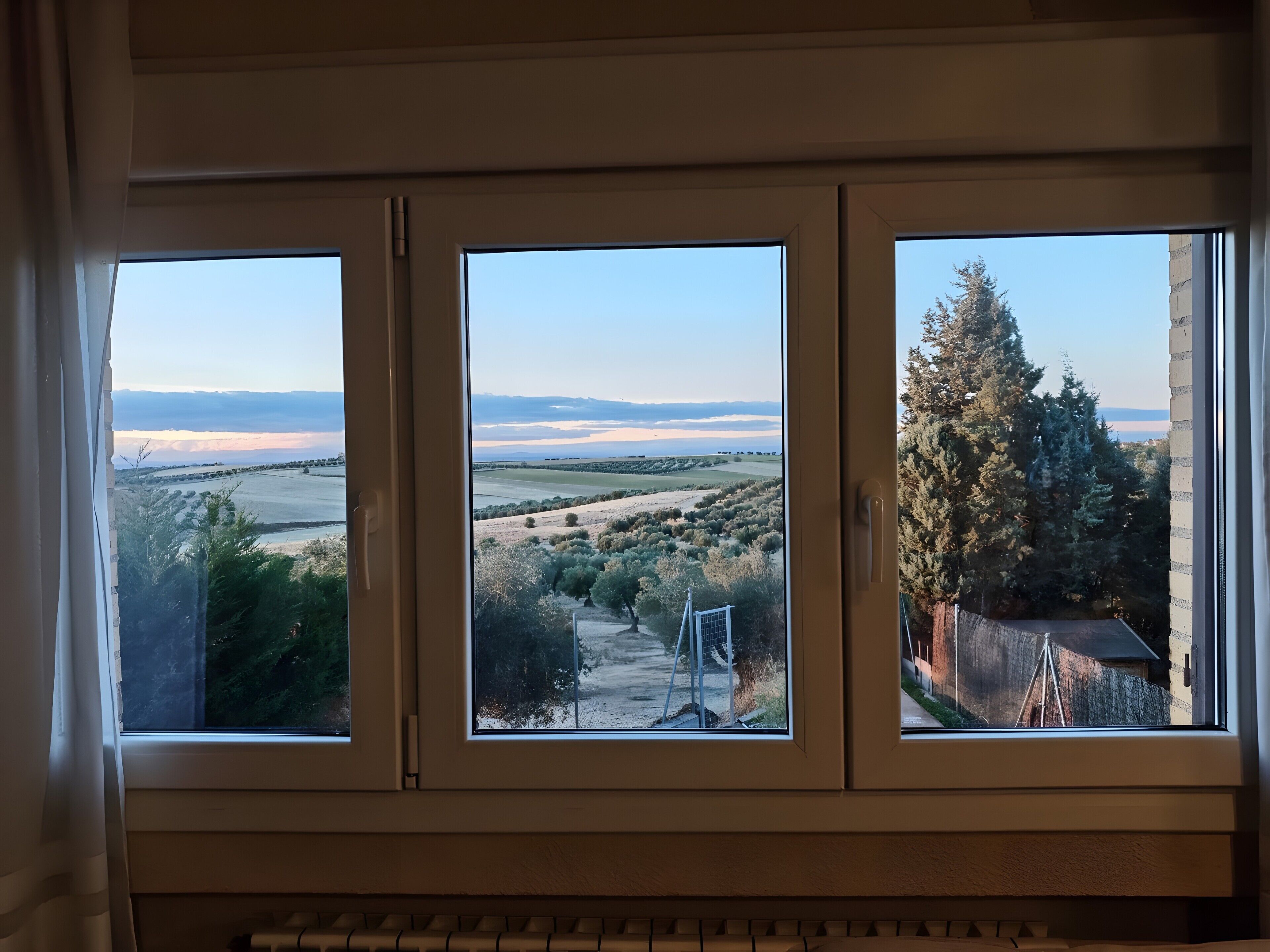 Een kamer met drie ramen met uitzicht op een landschap.