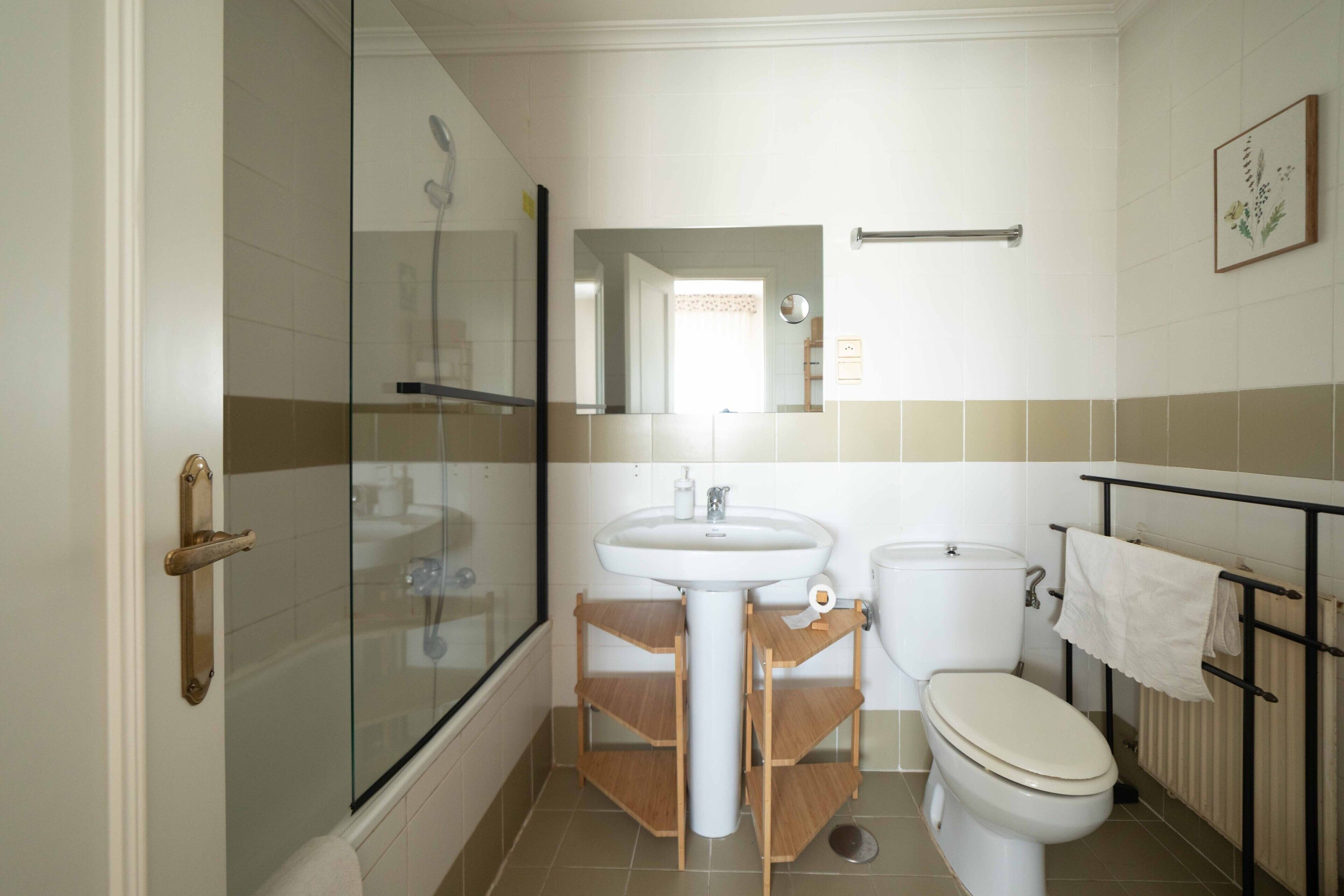 Een badkamer met een douchecabine van glas, een wastafel, een toilet en een handdoekhouder.
