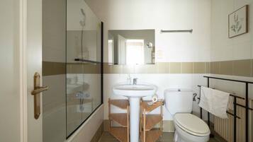 Een badkamer met een douchecabine van glas, een wastafel, een toilet en een handdoekhouder.