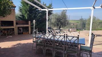 Een terras buiten met een tafel en stoelen, omgeven door een witte pergola.