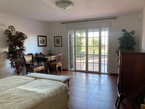 A room with a bed, a desk, a chair, and a large sliding glass door leading to an outdoor area.