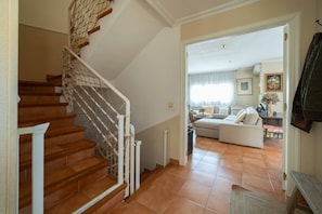 A staircase with a wooden finish and white railings, leading to a living room with a sofa and a coffee table.