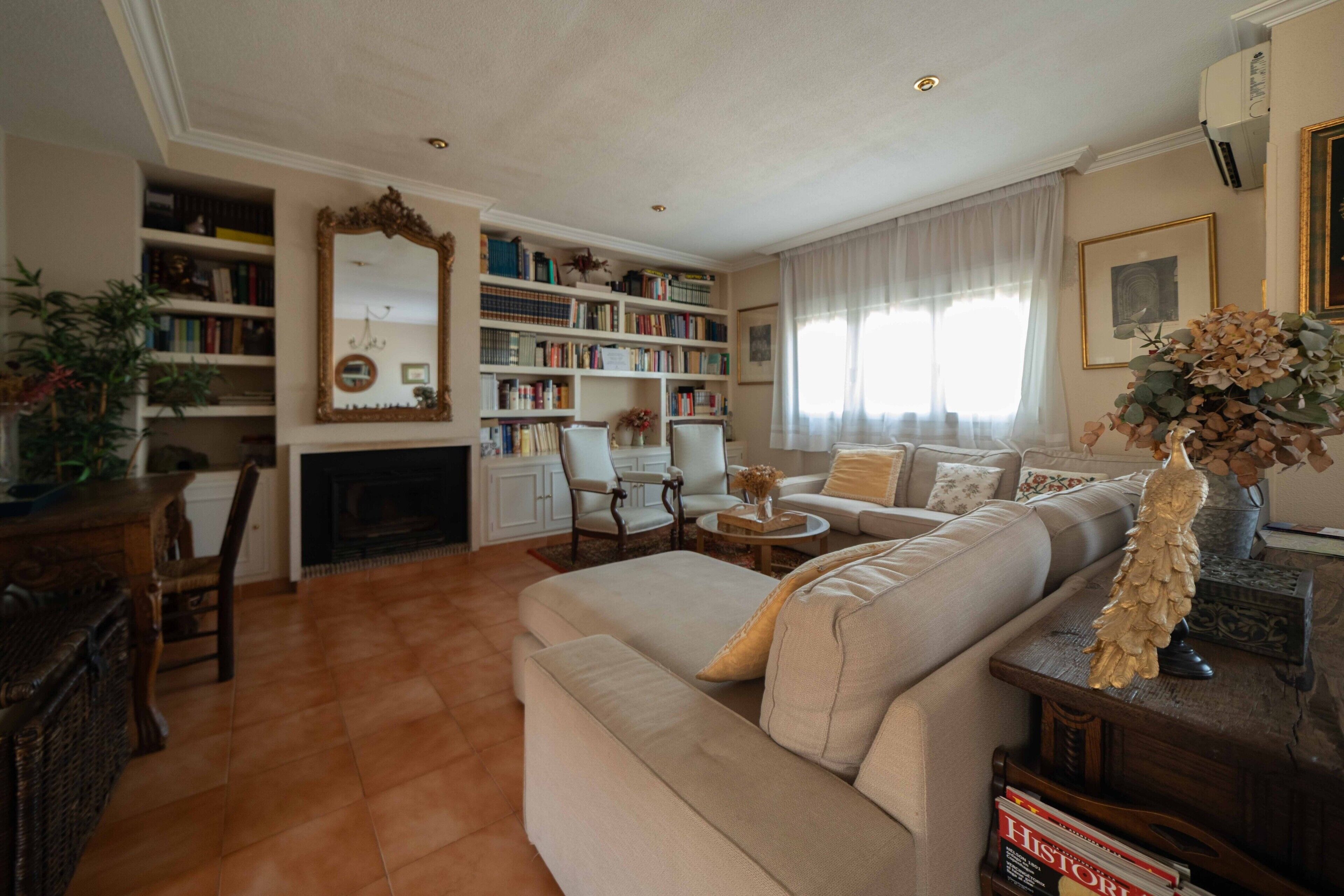 Een woonkamer met een open haard, boekenkasten, een bank en een eethoek.
