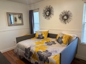 Una camera da letto con un letto, due applique, una finestra con persiane e uno specchio a parete.