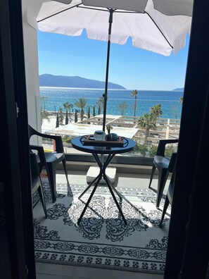 Ein Balkon mit Tisch und Stühlen mit Blick auf einen Strand und Palmen.