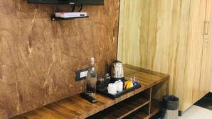 Una habitación moderna con un televisor de pantalla plana montado en una pared de madera, un estante pequeño debajo y un armario de madera a la derecha.