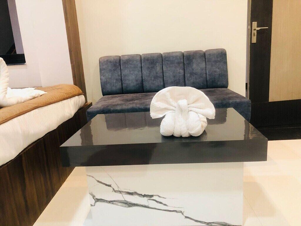 A modern room with a grey sofa, a white towel on a bed, and a marble coffee table.