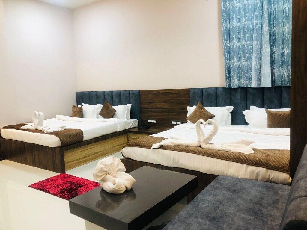 A hotel room with two beds, a sofa, a coffee table, and a red rug.